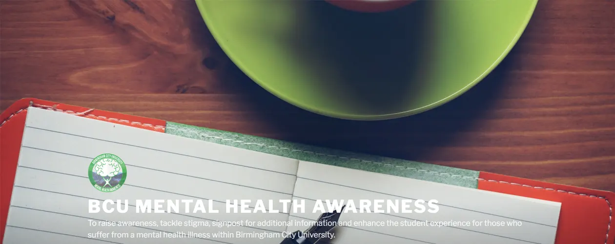 Full-width version of the BCU Mental Health Awareness homepage showing the same mug and notebook banner image with overlay text.